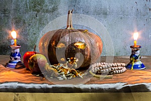 Halloween still life with pumpkins, apple, candles and rosary