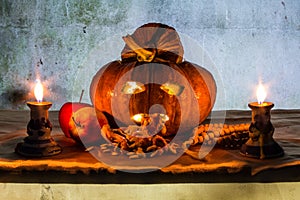 Halloween still life with pumpkins, apple, candles and rosary