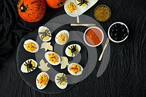 Halloween stuffed eggs with cheese and mustard on a black stone.