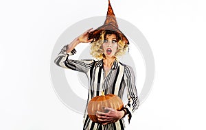 Halloween surprised witch with magic pumpkin. Beautiful woman in witches hat with Jack-o-lantern.