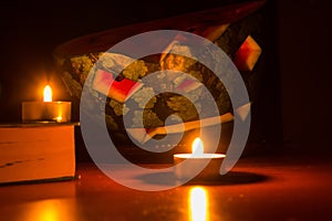 Halloween symbol, water-melon with carved red smiling face. Burning candles and books on wooden table, dark background.