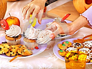 Halloween table with trick or treat and child hands.