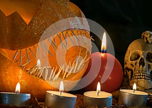 Halloween theme, carved pumpkin with a scary smile, burning candles, spiders and cobwebs, awful skulls, decoration and holiday