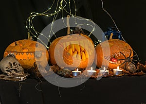 Halloween theme, carved pumpkin with a scary smile, burning candles, spiders and cobwebs, awful skulls, decoration and holiday