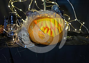 Halloween theme, carved pumpkin with a scary smile, burning candles, spiders and cobwebs, awful skulls, decoration and holiday