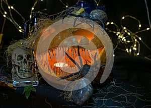 Halloween theme, carved pumpkin with a scary smile, burning candles, spiders and cobwebs, awful skulls, decoration and holiday