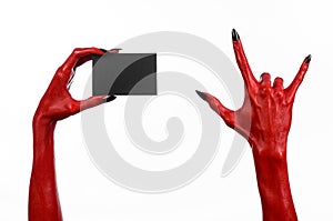 Halloween theme: Red devil hand with black nails holding a blank black card on a white background