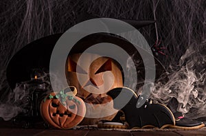 Halloween themed composition with pumpkin, candle, smoke and gingerbread