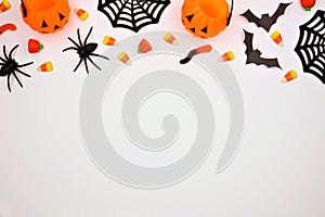 Halloween top border of candy and decor, flat lay over white