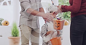 Halloween, trick or treat candy with parents shaking hands and kid in costume on holiday with lantern basket. Child