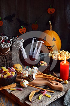 Halloween trick or treat party. Funny delicious sweets and pumpkin on wooden background - muffins, cupcakes, marshmallows, popcorn