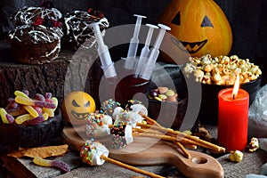 Halloween trick or treat party. Funny delicious sweets and pumpkin on wooden background - muffins, cupcakes, marshmallows, popcorn