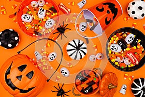 Halloween trick or treat scene with jack o lantern pails and candy over an orange background