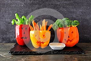 Halloween vegetables and dip in Jack o Lantern peppers on a dark background