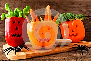 Halloween vegetables and dip in Jack o Lantern peppers on wood