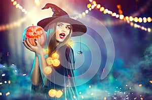 Halloween. Witch with a carved pumpkin and magic lights