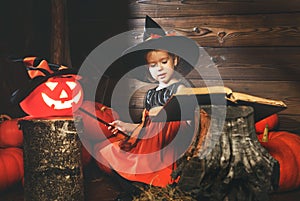Halloween. witch child conjures with book of spells, magic wand and pumpkins