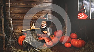 Halloween. witch child conjures with book of spells, magic wand and pumpkins photo