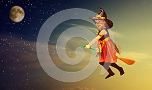 Halloween. Witch child flying on broomstick at sunset night sky.