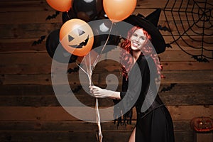 Halloween Witch Concept - Beautiful caucasian woman in witch costumes celebrating Halloween posing with posing with orange and bla