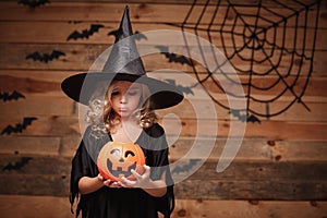 Halloween Witch concept - little caucasian witch child disappointing with no candy in halloween candy pumpkin jar. over photo