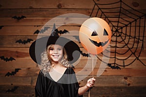 Halloween Witch concept - little caucasian witch child enjoy with halloween balloon. over bat and spider web background.