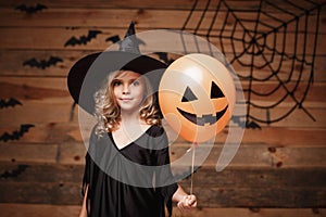 Halloween Witch concept - little caucasian witch child enjoy with halloween balloon. over bat and spider web background.