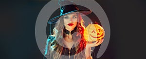 Halloween Witch holding Pumpkin lantern over black background. Decoration, hanging Jack-o-Lantern Pumpkin