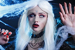 Halloween witch with long white hair wearing spider web