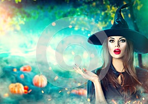 Halloween witch pointing hand over dark magic field with pumpkins