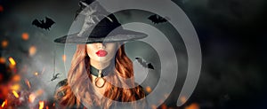 Halloween. witch portrait. Beautiful woman in witches hat with long curly red hair