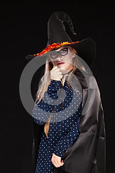 Halloween Witch with Pumpkin on black backgroundin a fancy mask. Beautiful young surprised woman in witches hat and