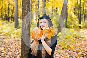 Halloween Witch with Pumpkin in a forest.