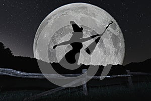 Halloween witch silhouette flying with broomstick. Full Moon.
