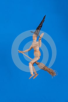 Halloween witch waving riding a witches broom wearing a black pointed witches hat on blue background