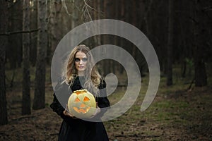 Halloween. yellow pumpkin. beautiful girl in a black dress in the forest.