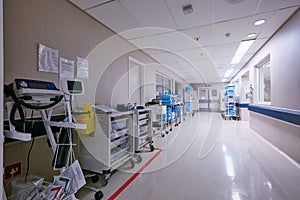 The hallway of healing. Shot of an empty passage way with medical equipment alongside the walls at a hospital.