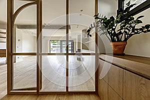 Hallway of a home with an antechamber with glass and wood display cabinets, interior floors and a large empty living room in the