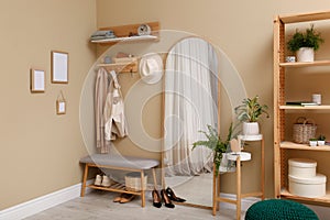 Hallway interior with furniture, accessories and wooden hanger for keys on beige wall