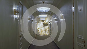 A hallway with lights and a marble wall in hotel.