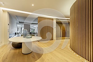 Hallway of luxury home with round table with vases, slatted walls