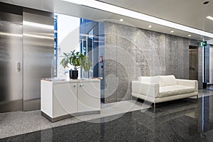 Hallway of an office in an office building with polished two-tone granite floors and white leather sofas