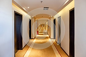 Hallway straight with the door and golden lighting illuminated in the hotel