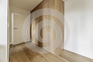 Hallway to a bedroom with fitted wardrobes with custom made light oak doors, white painted walls and light wood floors