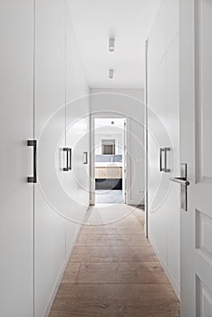 Hallway walk-in closet with white wood cabinets with metal pulls