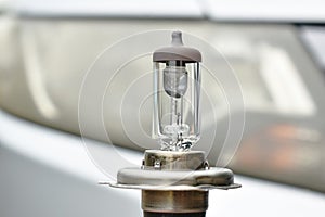 Halogen light bulb vehicle spare parts on car head lamp background