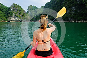 Halong Bay / Vietnam, 06/11/2017: Woman on kayak paddling through karst islands and dense jungle in Halong Bay / Cat Ba island