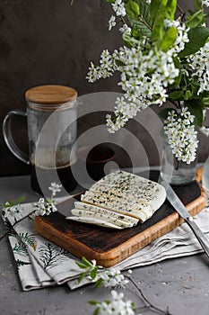 Haloumi cheese cut into pieces on a dark wooden board next to spring flowers