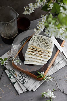 Haloumi cheese cut into pieces on a dark wooden board next to spring flowers
