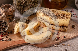 Halumi cheese with spices is sliced â€‹â€‹on a wooden board. Decorated with spices. In the background glass jars with spices and